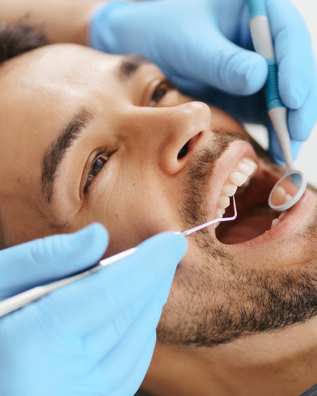 Smiling young man sitting in dentist chair while doctor examining his teeth